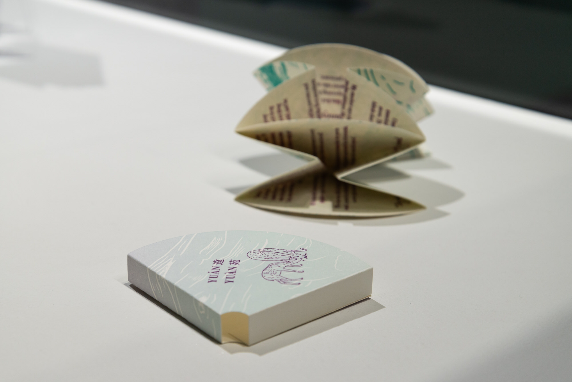 Cover sleeve for artist's book, printed in pale jade and lavender with an image of two deer grazing in deep violet